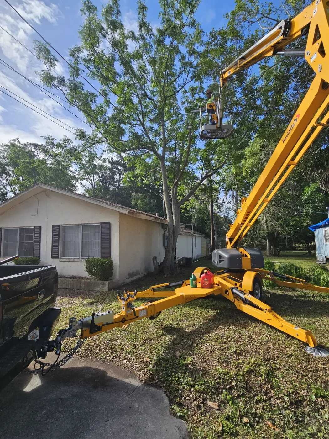 Tracked lift beside a house removing a storm-damaged tree